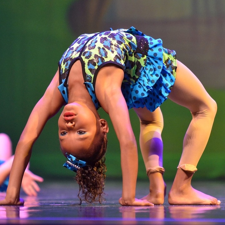Young girl doing backbend move.